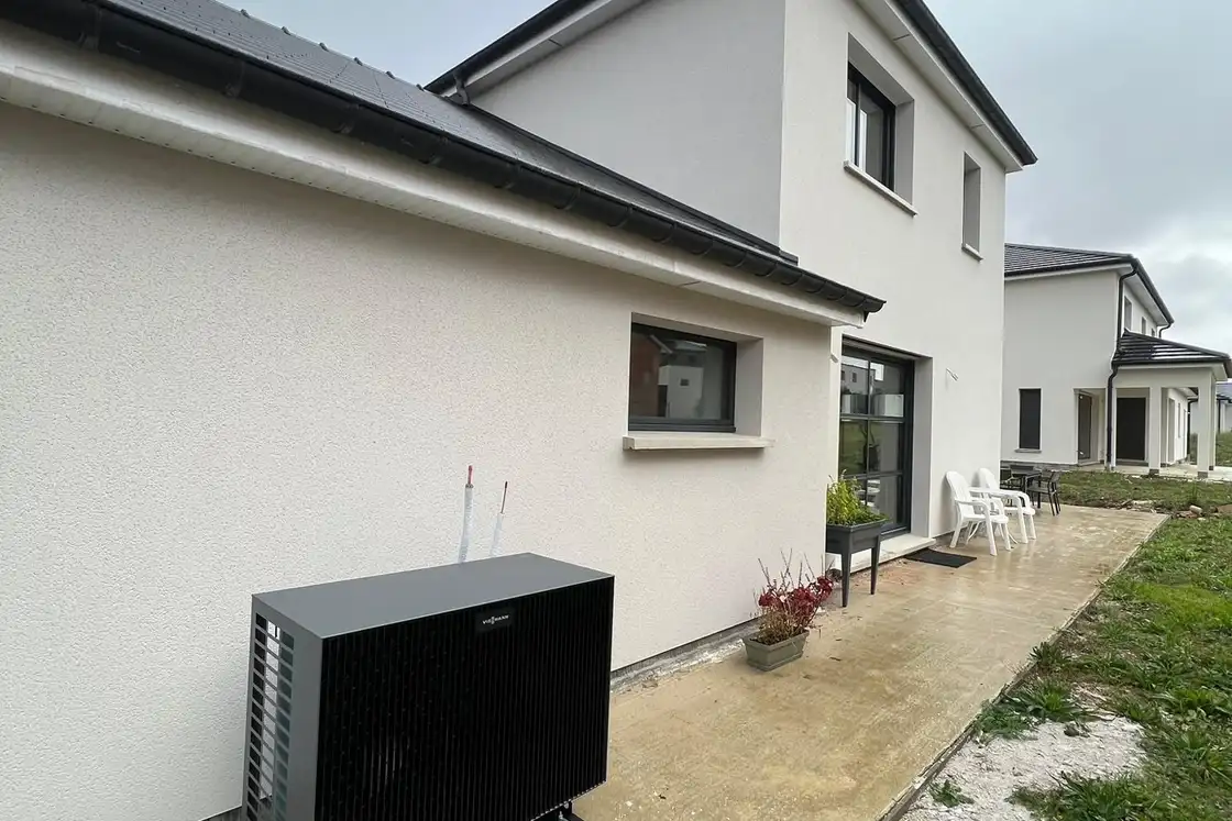 Unité extérieure de pompe à chaleur posée sur plots le long d’une maison récente